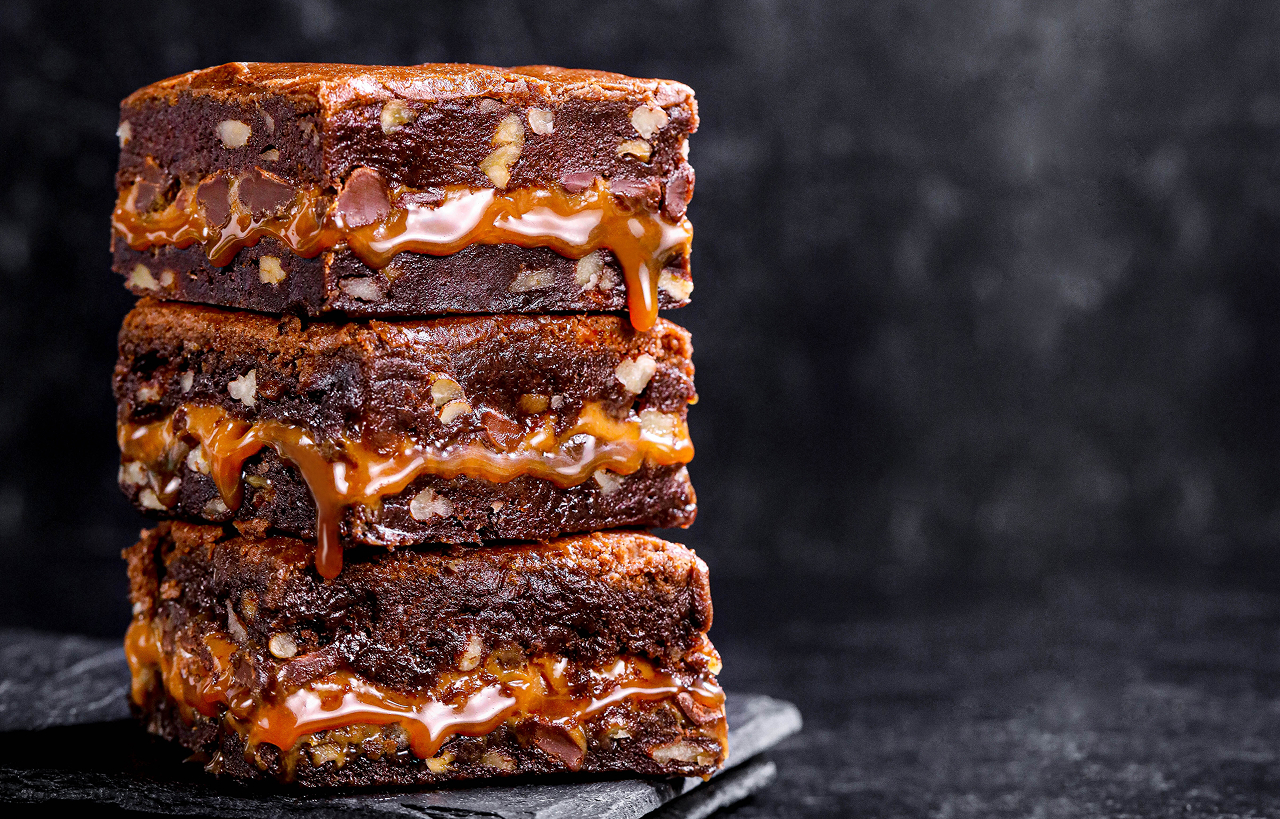 Stack of original Killer Brownie squares with caramel dripping down the sides