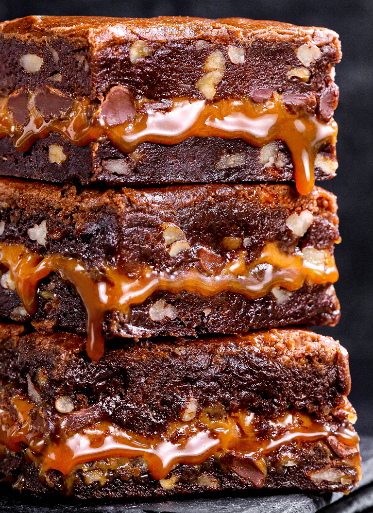 Stack of original Killer Brownie squares with caramel dripping down the sides